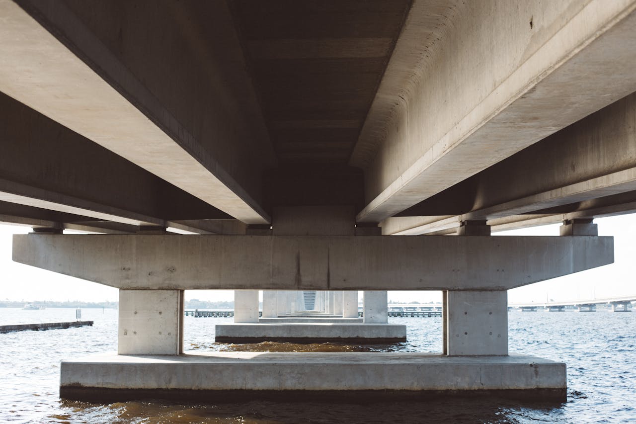 why-choose-us Modern concrete bridge over water, displaying architectural details and symmetry.